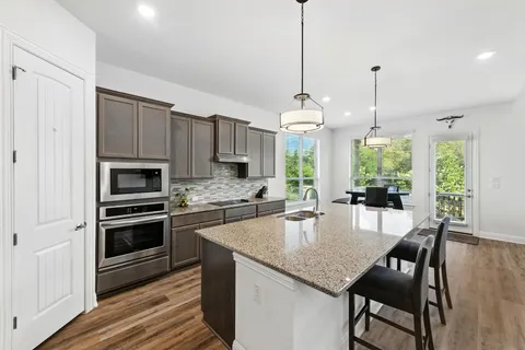a kitchen with stainless steel appliances granite countertop a stove a kitchen island a dining table and chairs