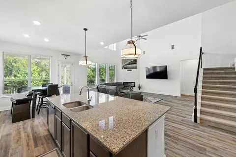 a kitchen with granite countertop a table chairs stove and wooden floor