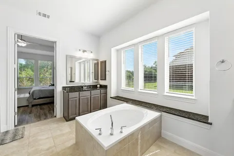 a large bathroom with a tub a sink and a window