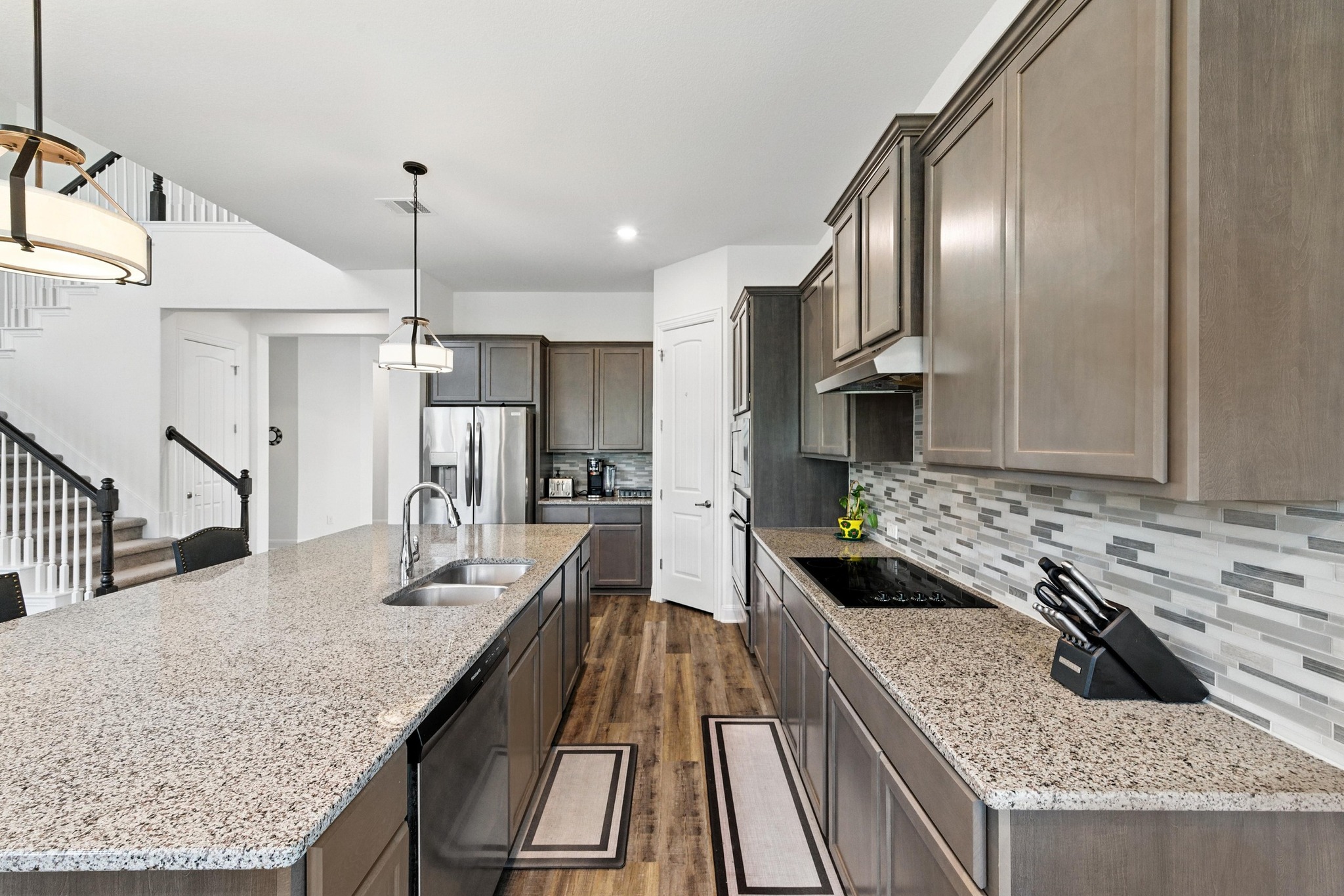 216 Tovas Secret Cove Georgetown, TX 78628 - Photo 9 of 39 Kitchen with appliances with stainless steel finishes, under cabinet range hood, dark wood-style flooring, light stone counters, and recessed lighting