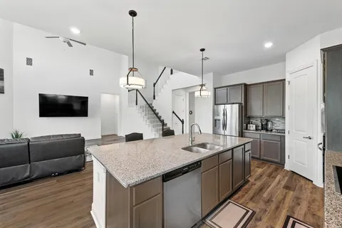 a kitchen with stainless steel appliances kitchen island granite countertop a sink a stove and a refrigerator