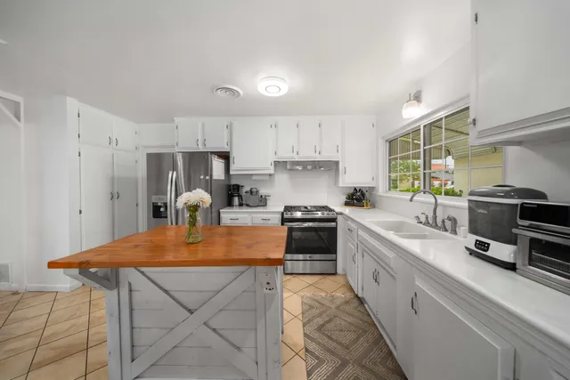 a kitchen with stainless steel appliances granite countertop a stove top oven a sink dishwasher and a refrigerator with wooden cabinets