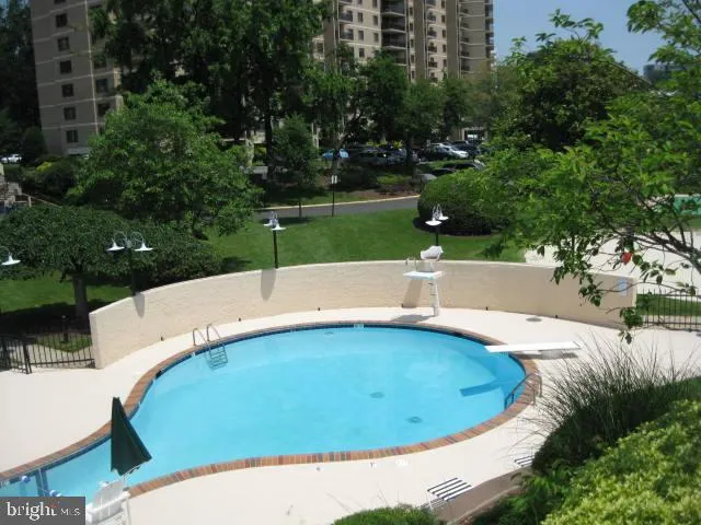 a patio with water view fountain plants and large trees