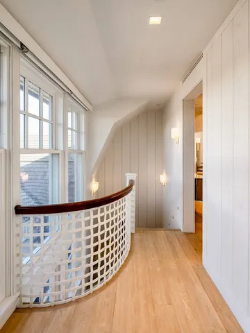 a view of a hallway with wooden floor and windows