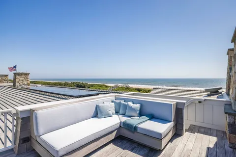 a view of roof deck with couches and ocean view
