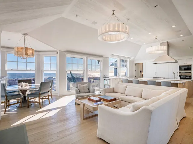 a living room with furniture kitchen view and a large window