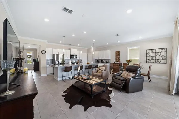 a living room with lots of furniture and a view of kitchen appliances