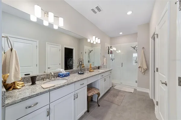 a bathroom with a granite countertop double vanity sink a mirror and shower