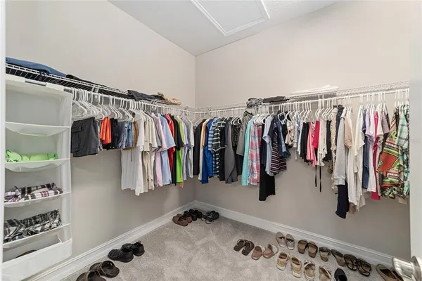 a view of walk in closet with clothes and shoes