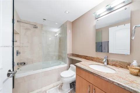 a bathroom with a granite countertop sink toilet mirror and bathtub
