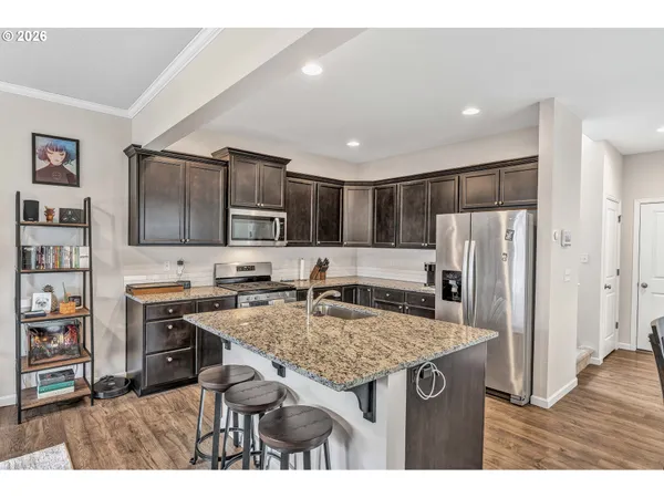 a kitchen with stainless steel appliances granite countertop a refrigerator a stove and a sink with wooden floor