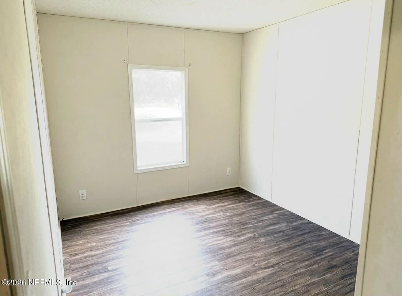 1670 Dennis Howell Road Perry, FL 32348 - Photo 11 of 15 an empty room with wooden floor and windows