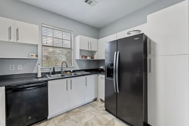 a kitchen with stainless steel appliances granite countertop a refrigerator a sink a stove and white cabinets