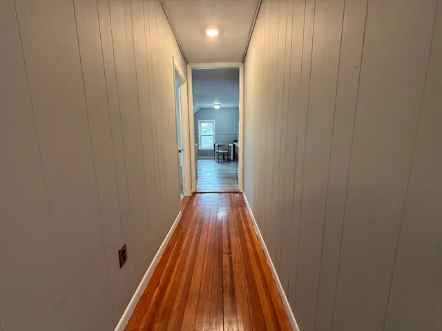 a view of a hallway with wooden floor and a bathroom