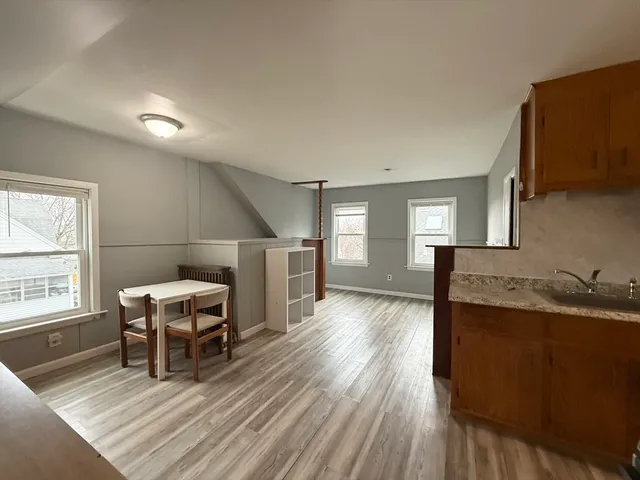 a living room with stainless steel appliances granite countertop furniture wooden floor and a window
