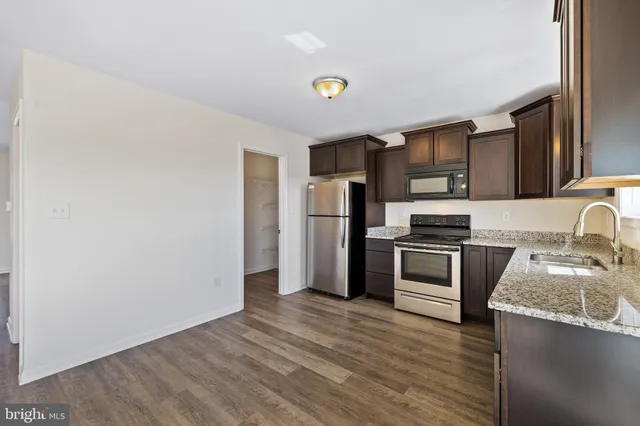 a kitchen with granite countertop stainless steel appliances a refrigerator and a sink