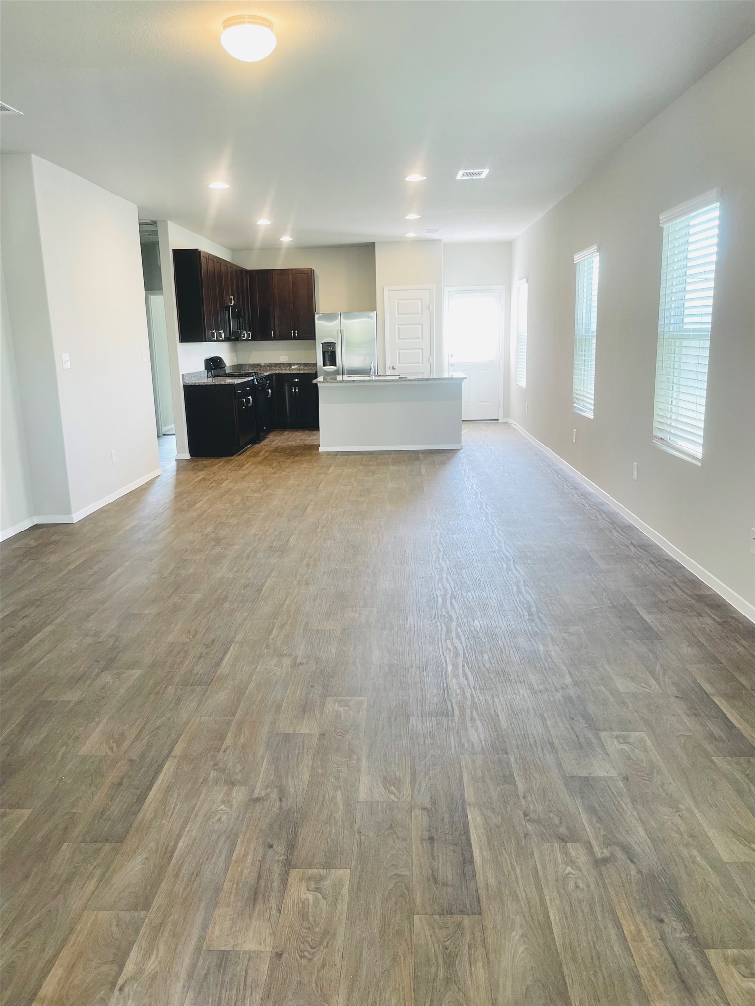 117 Huckleberry Lane Elgin, TX 78621 - Photo 3 of 34 Open plan living room featuring lots of natural light & wood finished floors and baseboards with recessed lighting