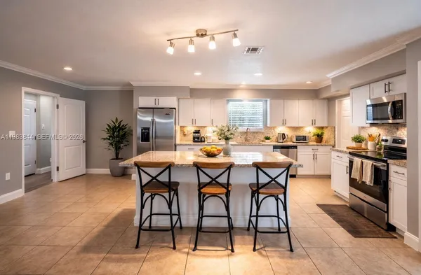 a open kitchen with stainless steel appliances kitchen island granite countertop a sink a stove a dining table and chairs