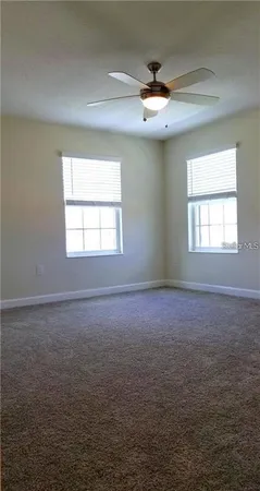 en empty room with windows and chandelier fan