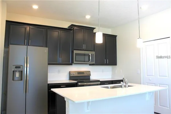 a kitchen with granite countertop a refrigerator and a sink