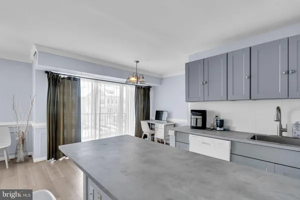 a large white kitchen with granite countertop a sink white cabinets and white appliances