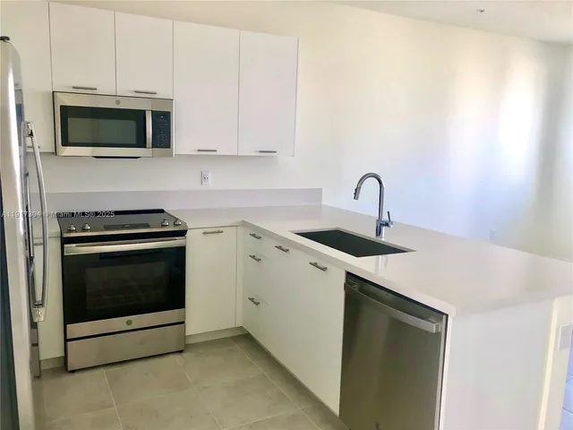 a kitchen with stainless steel appliances a stove a microwave a sink and cabinets