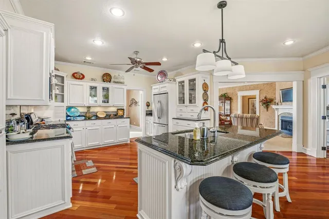 a kitchen with stainless steel appliances granite countertop a stove a sink and a dining table with wooden floor