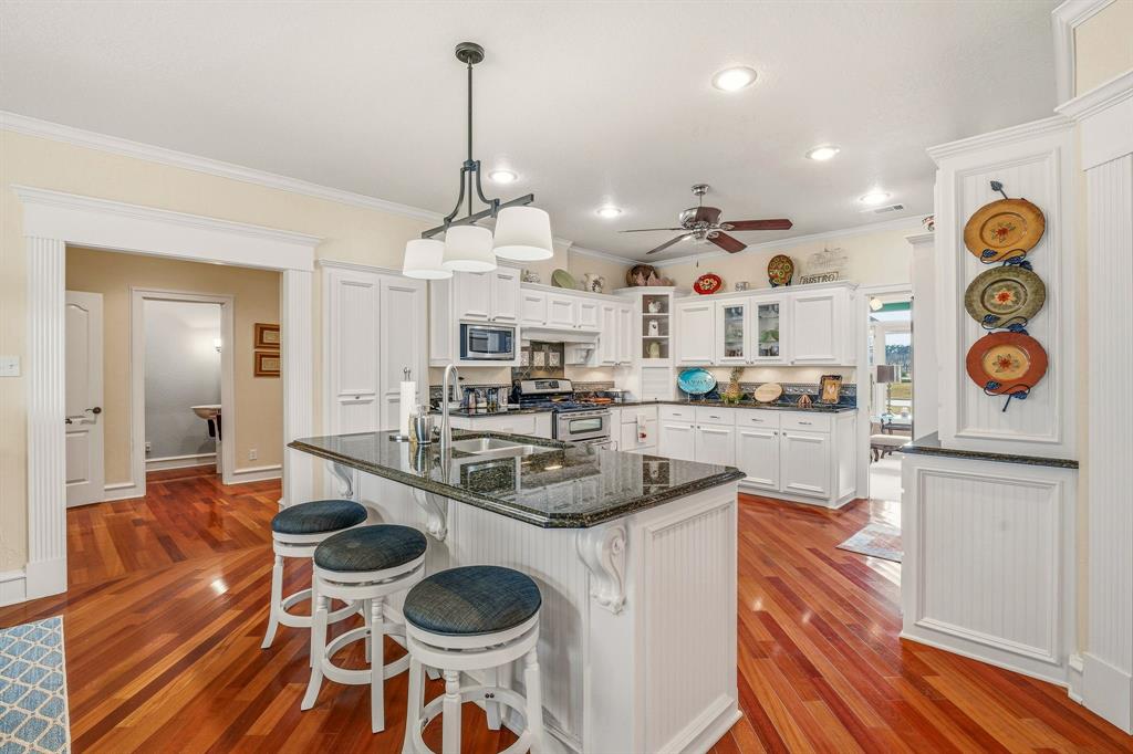 501 County Road 103 Comanche, TX 76442 - Photo 17 of 40 a kitchen with stainless steel appliances granite countertop a stove a sink and a dining table with wooden floor