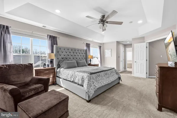 a bedroom with a large bed couch and windows