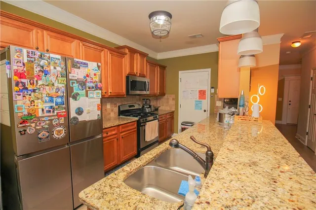 a kitchen with stainless steel appliances granite countertop a refrigerator a stove and a sink with wooden floor