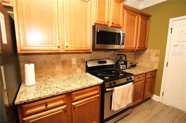 a kitchen with stainless steel appliances granite countertop a stove a sink and a microwave