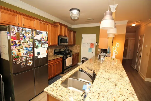 a kitchen with stainless steel appliances granite countertop a refrigerator stove top oven and sink