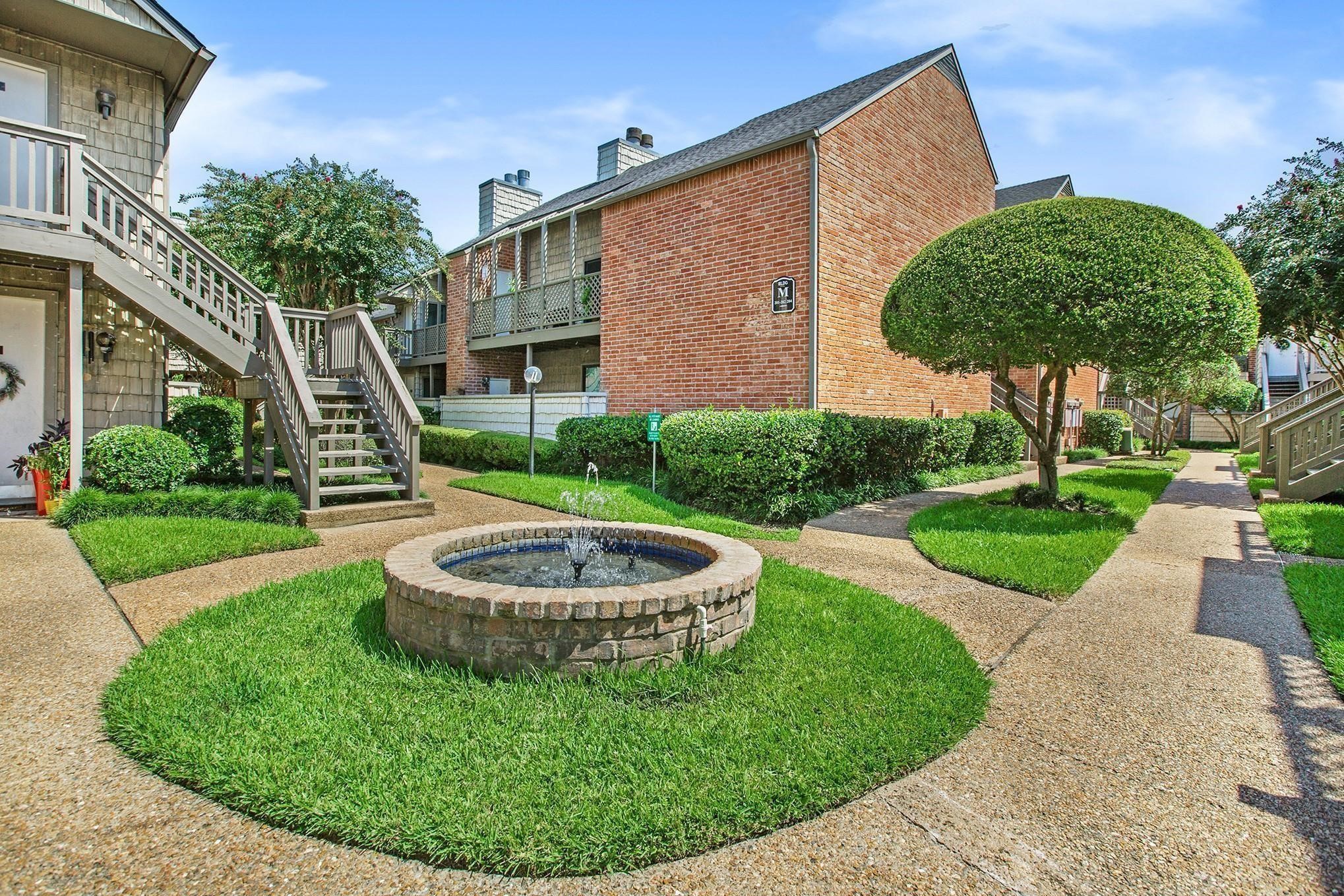 a view of a house with a small yard and a fountain