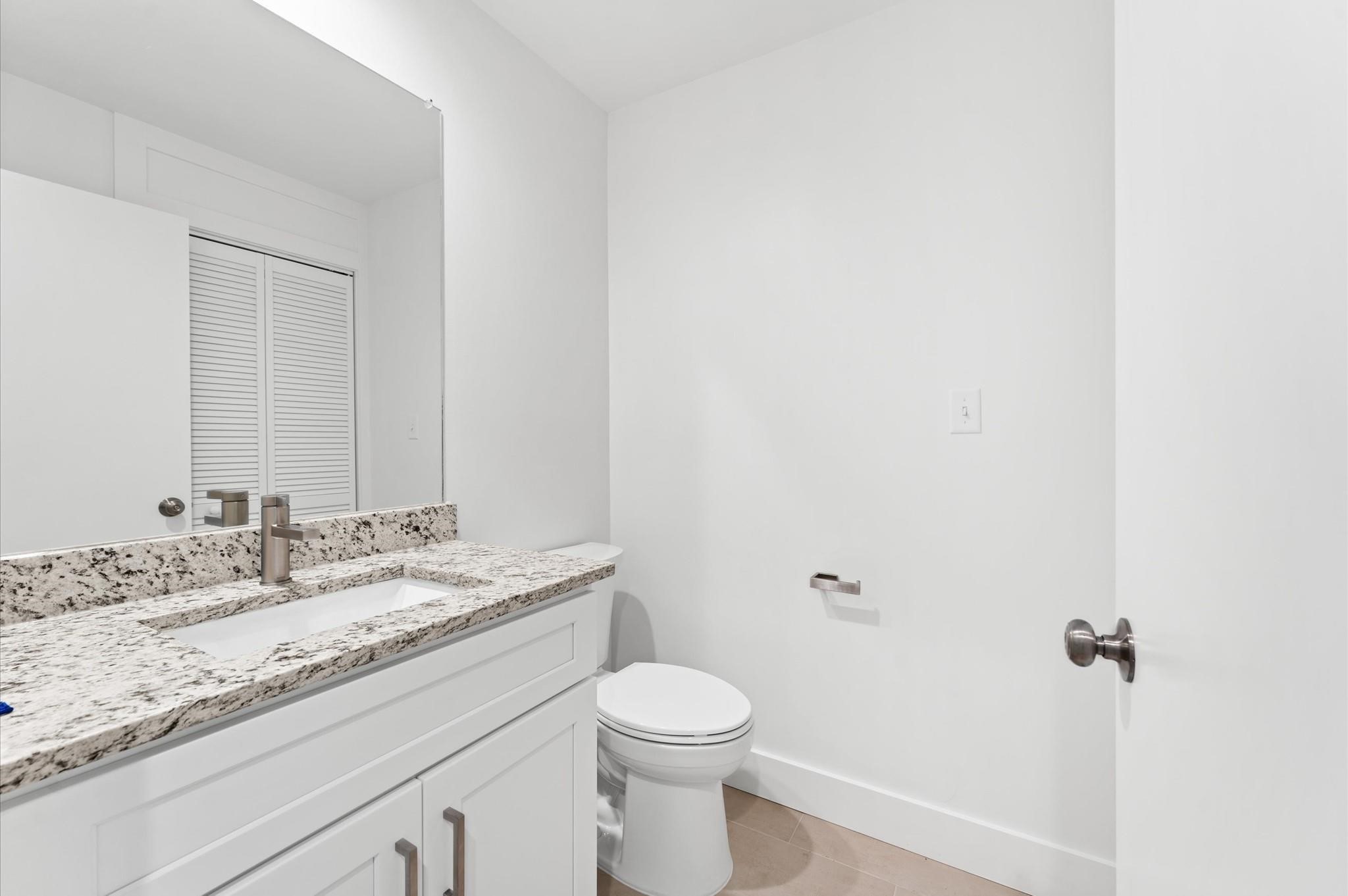 2829 Timmons Lane, Unit 202 Houston, TX 77027 - Photo 9 of 16 a bathroom with a granite countertop sink a toilet and a mirror