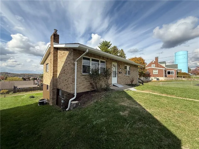 a view of a house with a big yard and a large tree
