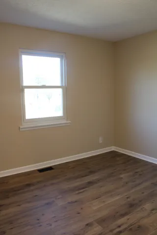 an empty room with wooden floor and a window