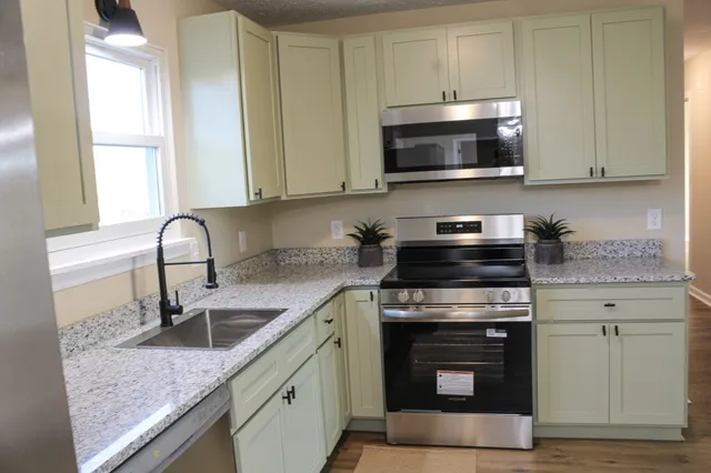 a kitchen with stainless steel appliances granite countertop a sink stove and microwave