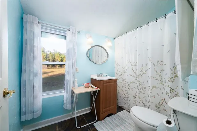a bathroom with a granite countertop toilet a sink and a mirror