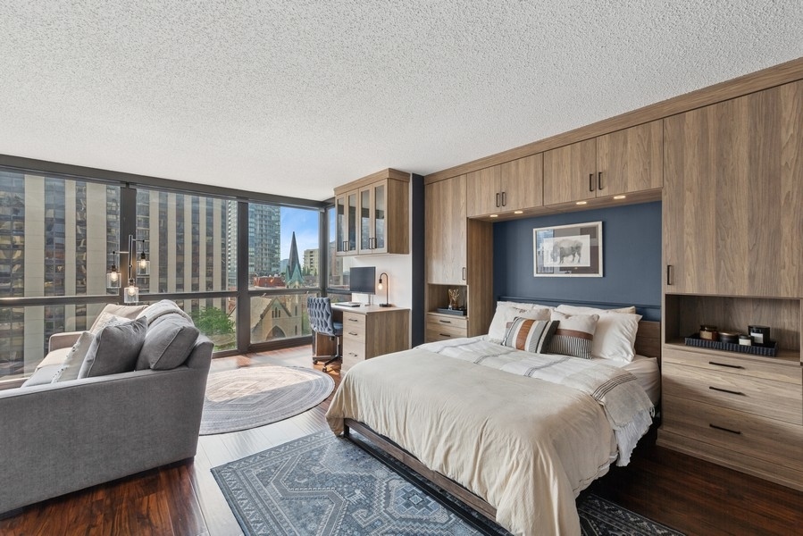 1122 North Clark Street, Unit 1002 Chicago, IL 60610 - Photo 11 of 14 a spacious bedroom with a bed a couch and a potted plant on the dresser