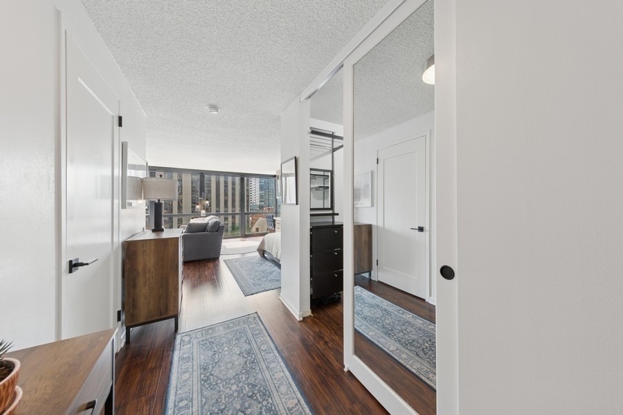1122 North Clark Street, Unit 1002 Chicago, IL 60610 - Photo 2 of 14 a walk in closet with wooden floor and glass door