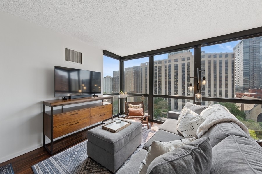 1122 North Clark Street, Unit 1002 Chicago, IL 60610 - Photo 4 of 14 a living room with furniture and a flat screen tv
