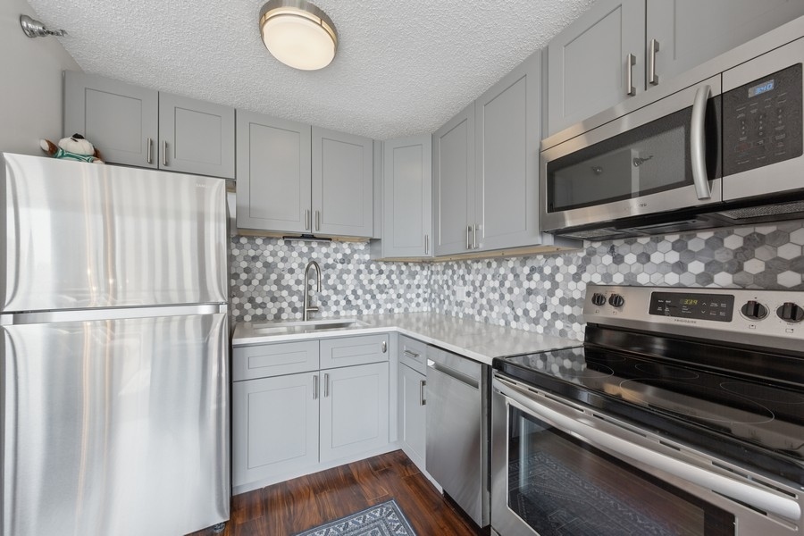 1122 North Clark Street, Unit 1002 Chicago, IL 60610 - Photo 9 of 14 a kitchen with stainless steel appliances a refrigerator sink and microwave