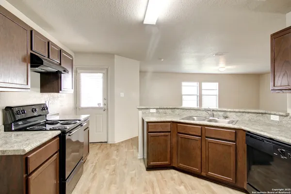 a kitchen with granite countertop a sink stove and refrigerator