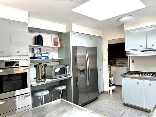a kitchen with stainless steel appliances kitchen island granite countertop a refrigerator stove and sink