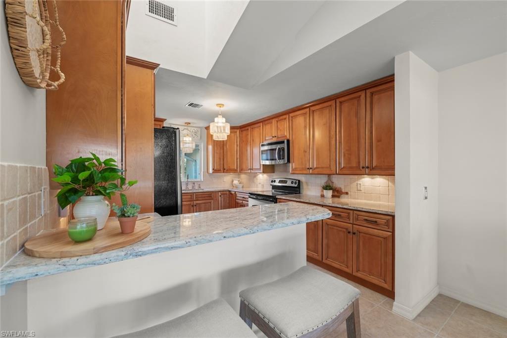 780 Waterford Drive, Unit 302 Naples, FL 34113 - Photo 11 of 47 a kitchen with stainless steel appliances granite countertop a sink a stove and a wooden cabinets