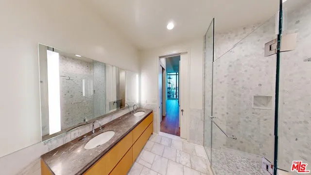 a spacious bathroom with a granite countertop double vanity sink a mirror and a shower