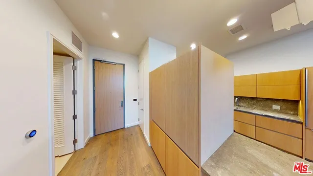 a view of a hallway with wooden floor and a kitchen space