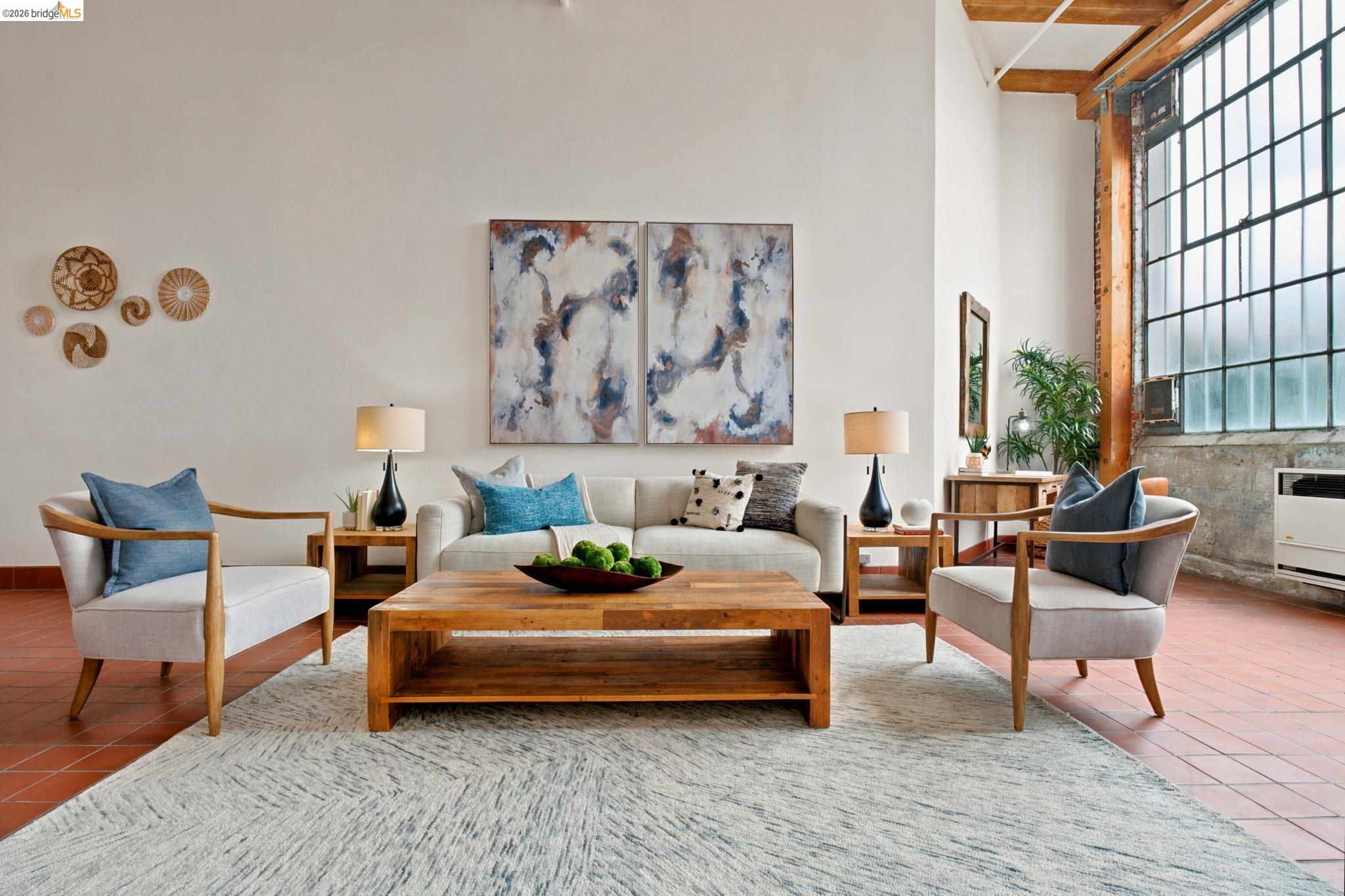 1920 Union Street, Unit 9 Oakland, CA 94607 - Photo 8 of 35 Spacious living area featuring high ceilings with exposed wood beams, large industrial-style windows, terra cotta tile flooring, and light-toned walls