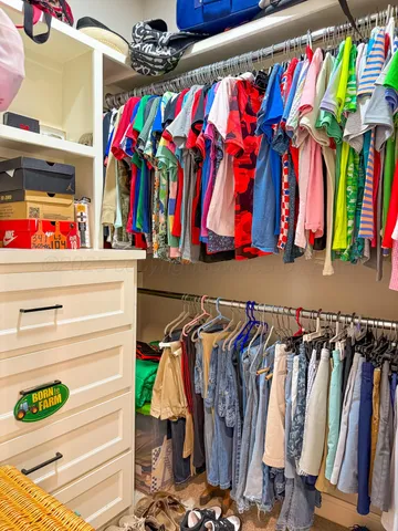 a view of walk in closet with clothes and shoes