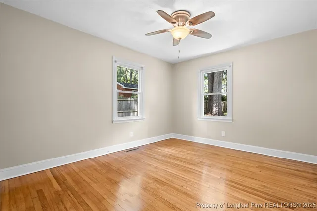 a view of an empty room with a window and a chandelier fan